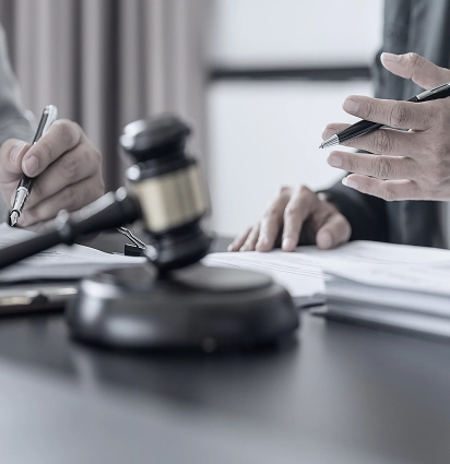 Gavel and hands at a legal/meeting table.